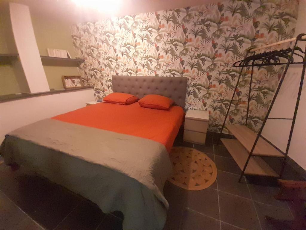 a bed with two orange pillows in a room at Gîte Olivia in Saint-Florent-sur-Auzonnet