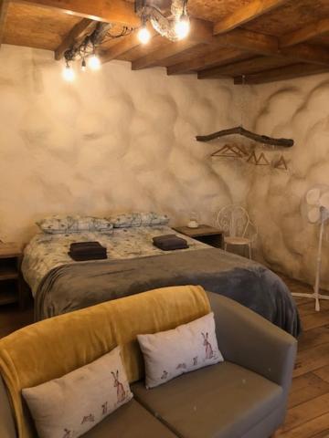 een slaapkamer met een bed, een bank en een stoel bij Rabbits 1or 2 bedroom hobbit style hillset earthen dartmoor eco home in South Brent