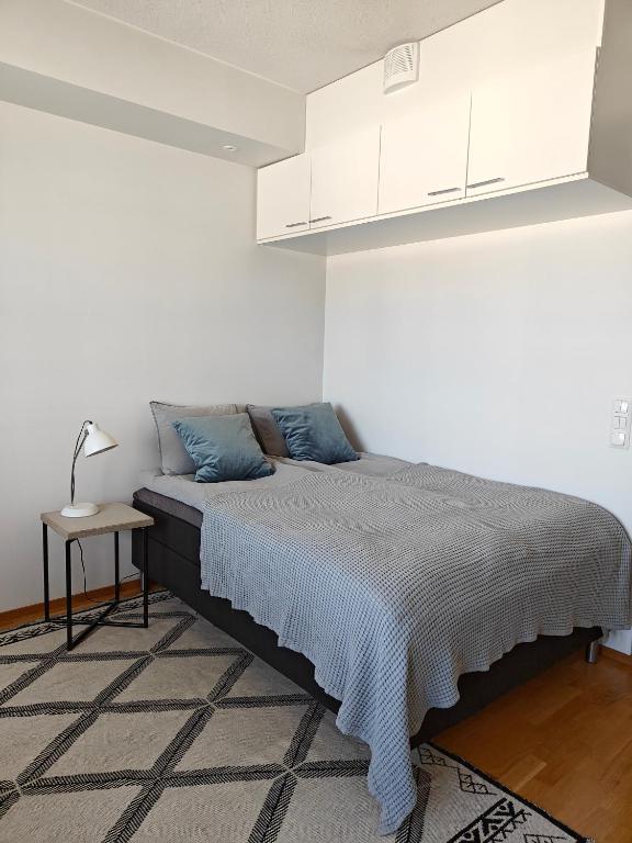 1 cama en una habitación blanca con una lámpara sobre una mesa en Sunstar Apartments, en Rovaniemi