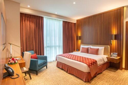 Cette chambre comprend un grand lit et une chaise. dans l'établissement Century Hotel Doha, à Doha