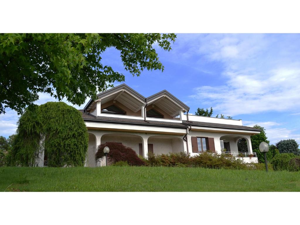 una casa blanca con césped verde y un árbol en B&B Villa Monterosa con Piscina, en Castronno