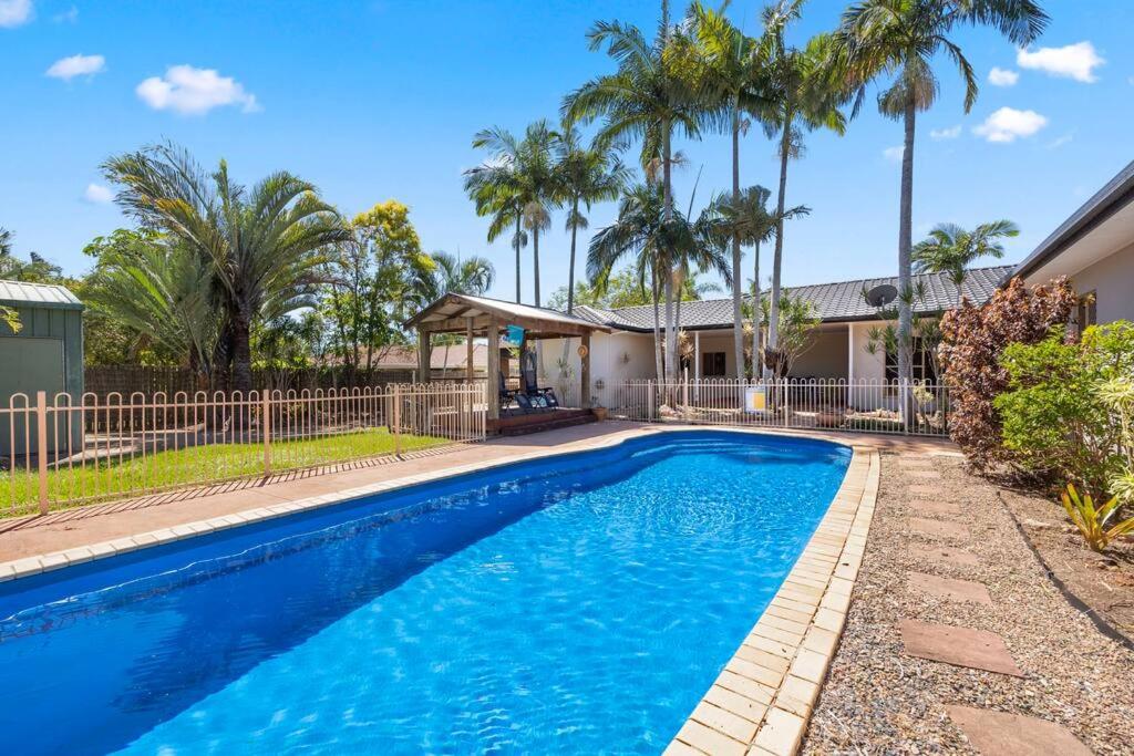 a swimming pool in front of a house with palm trees at 5 bedrooms with a pool in Kawungan