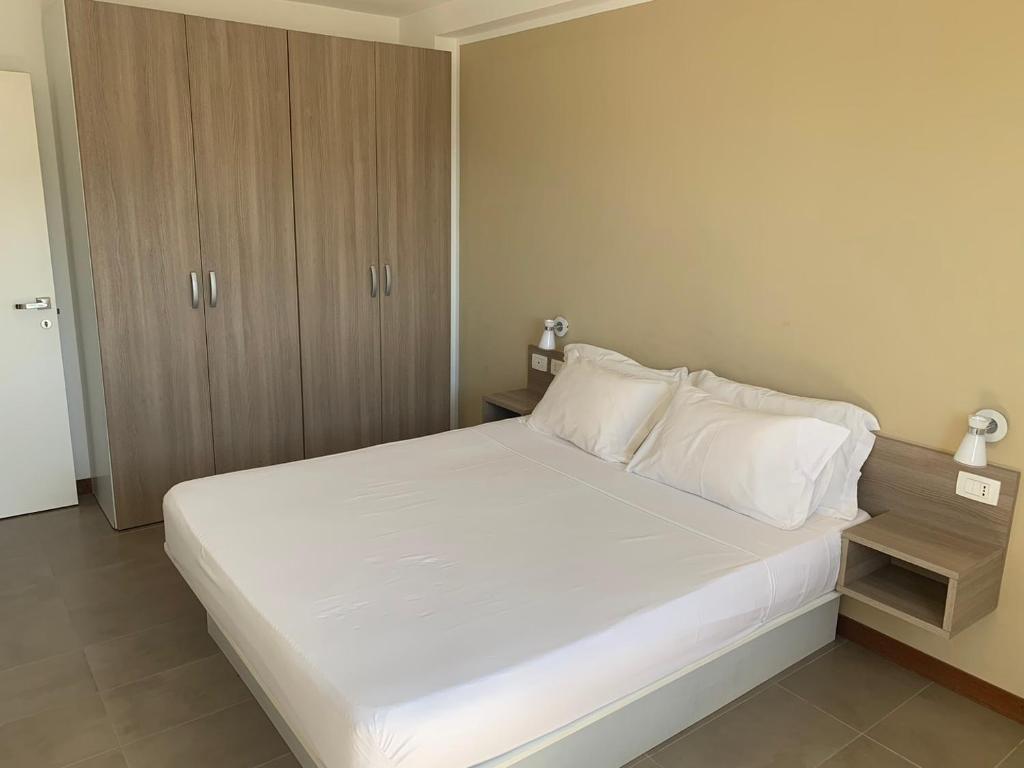 um quarto com uma grande cama branca e armários de madeira em Lazareto Oceanview em Mindelo