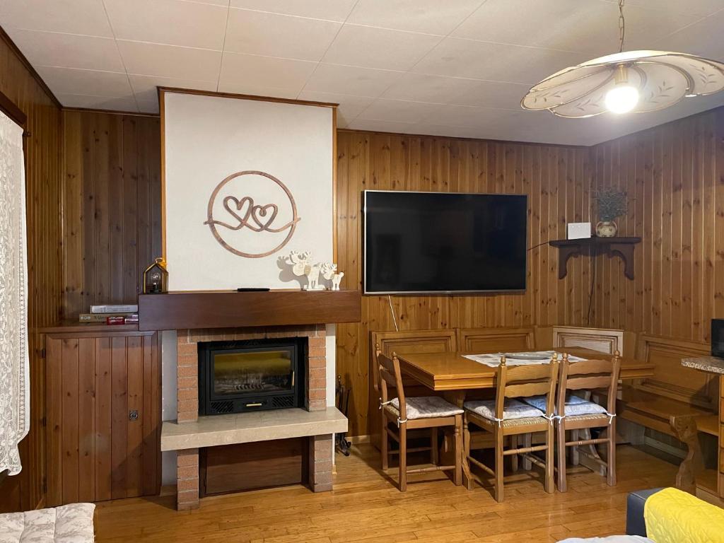 ein Wohnzimmer mit einem Kamin, einem Tisch und einem TV in der Unterkunft La casa di Pianca 2.0 in Piancavallo