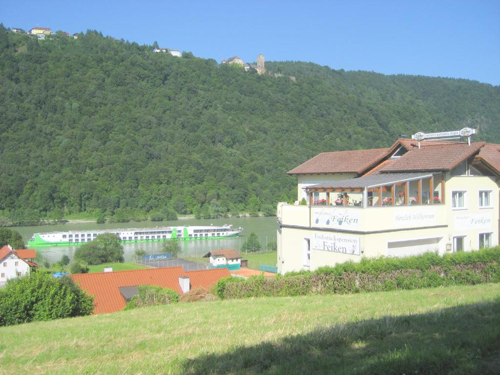 ein großes weißes Gebäude mit Menschen auf dem Balkon in der Unterkunft Pension Feiken in Wesenufer