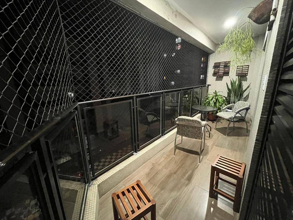 ein Balkon mit Stühlen und einem Tisch und einem Zaun in der Unterkunft Apartamento aconchegante e espaçoso! in Guarujá