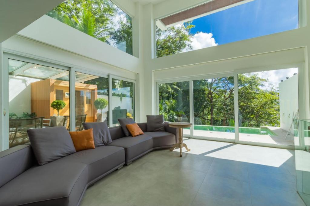 un soggiorno con divano grigio e ampie finestre di seaview patong private pool sauna 4br villa a Patong Beach