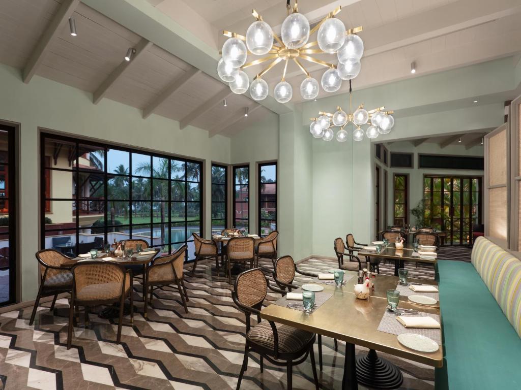 um restaurante com mesas e cadeiras e um lustre em ITC Grand Goa, a Luxury Collection Resort & Spa, Goa em Utorda