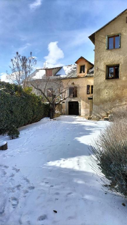 a yard covered in snow next to a building at Maison en Cerdagne avec belle vue in Enveitg