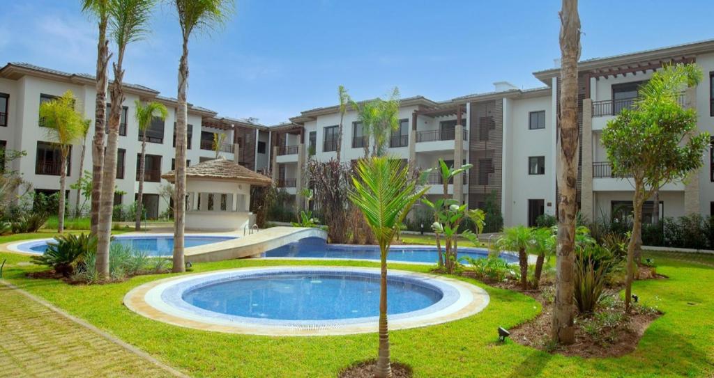 um complexo de apartamentos com piscina e palmeiras em El fal em Dar Bouazza