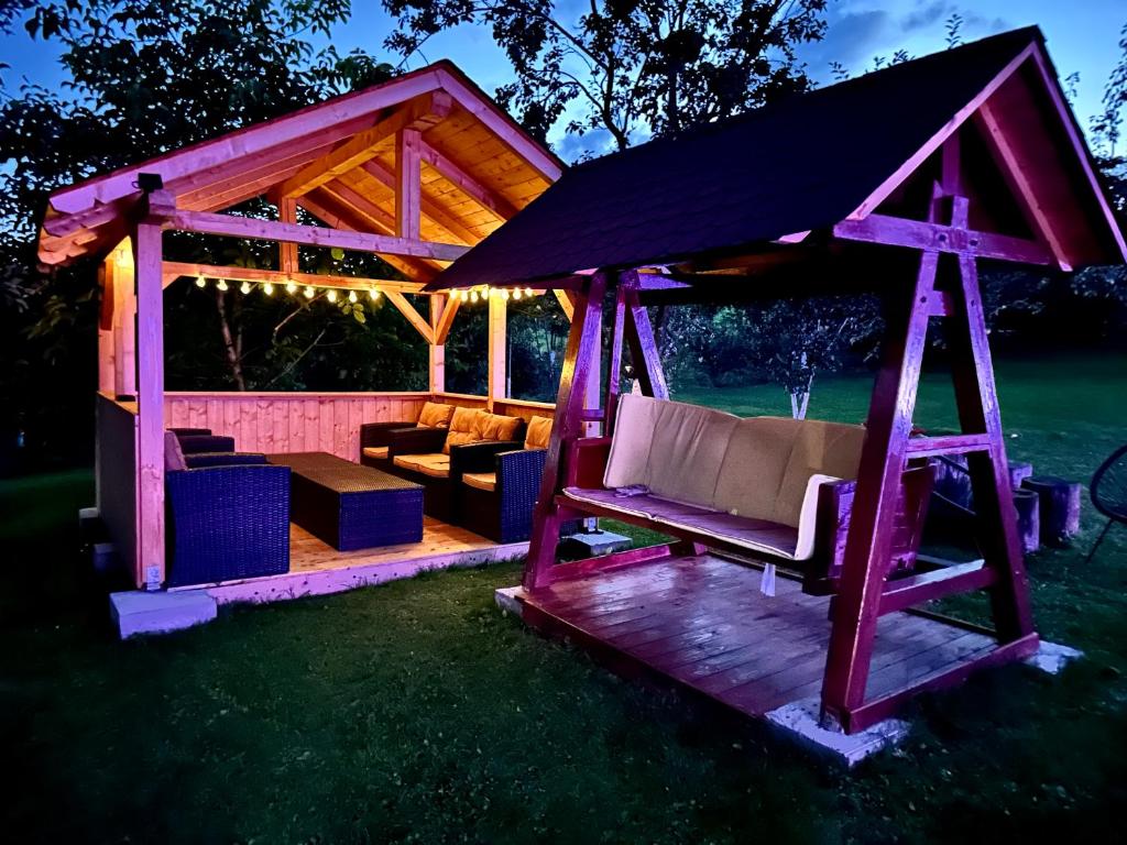 a wooden gazebo with a couch in the grass at Pensiunea Casa Eden in Mărişel