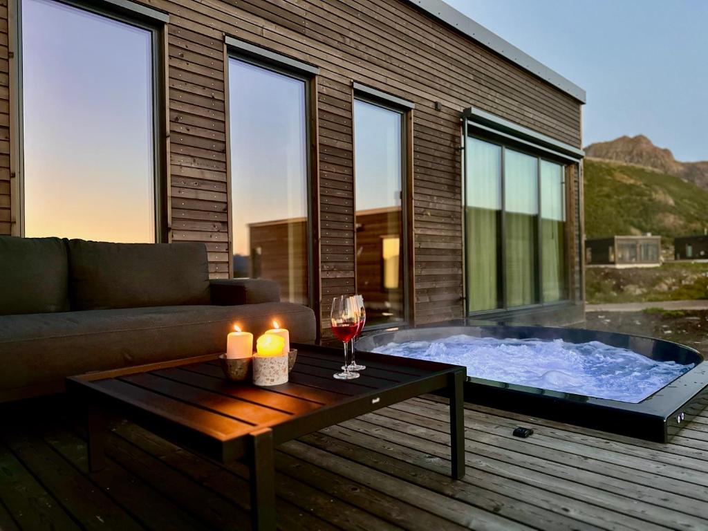 a hot tub with a glass of wine and candles on a deck at Luxury Lodge with jacuzzi and sauna in Kleppstad