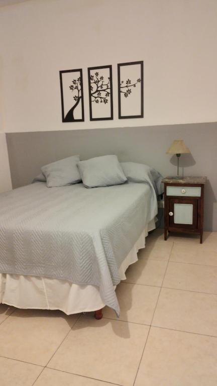 ein Schlafzimmer mit einem Bett mit vier Bildern an der Wand in der Unterkunft Floma in Neuquén