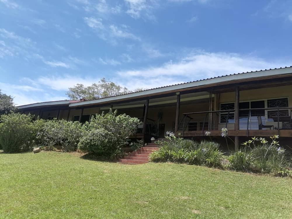 un bâtiment avec une terrasse couverte et une cour herbeuse dans l'établissement Redberry Guest House, à Mbabane