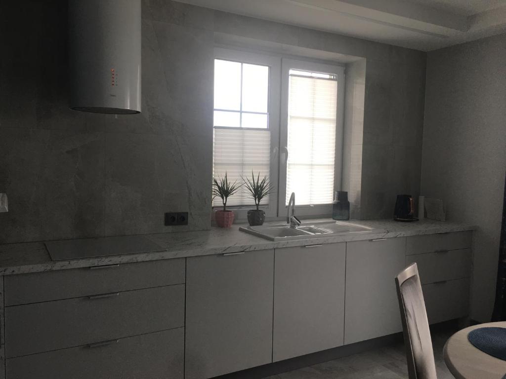 uma cozinha com armários brancos, um lavatório e uma janela em Apartament Janów Podlaski em Janów Podlaski