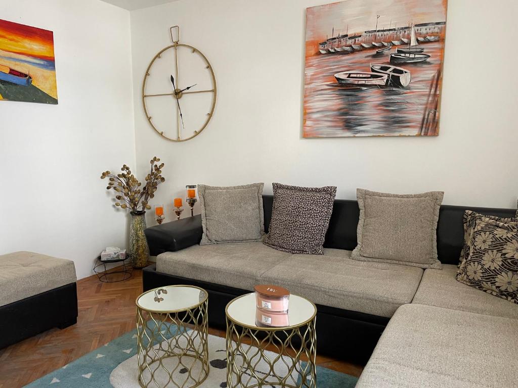 a living room with a couch and a clock on the wall at JOVAN APARTMAN in Rospi Ćuprija