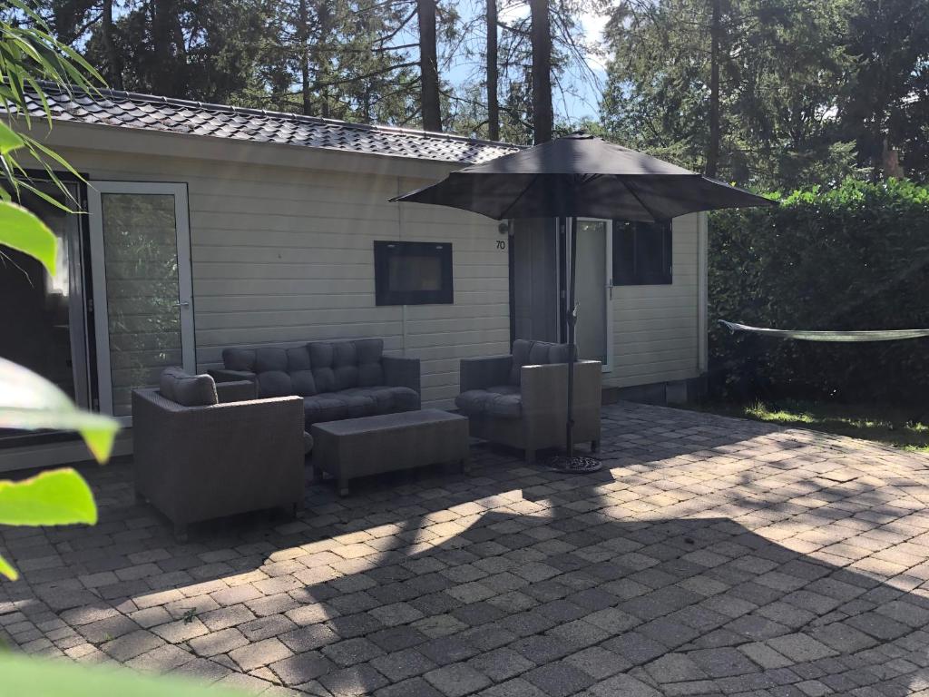 a patio with two chairs and an umbrella at Vrijstaand Chalet in Bospark in Hattemerbroek