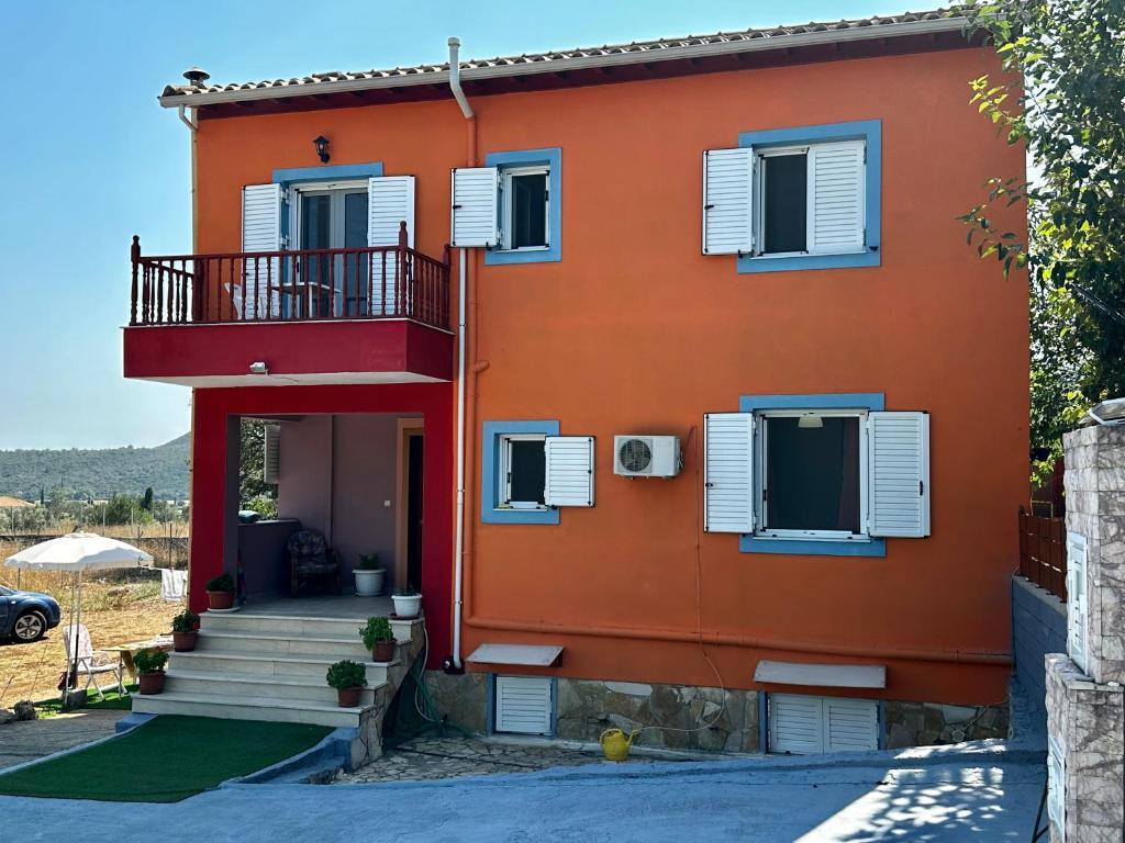 Casa de color naranja con ventanas blancas con persianas y escaleras en Sofias House, en Marantochori