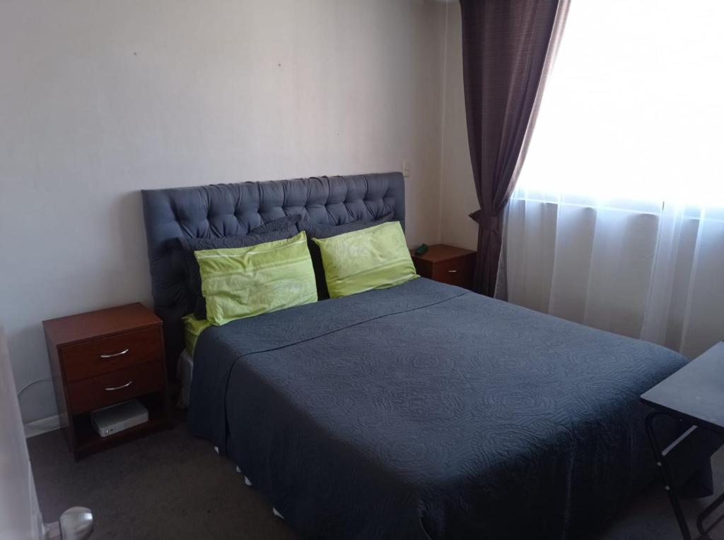 um quarto com uma cama azul com almofadas verdes e uma janela em Céntrico Departamento en Santiago em Santiago