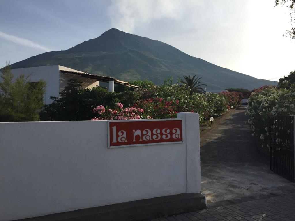 ein Schild an einer Wand mit einem Berg im Hintergrund in der Unterkunft Pensione La Nassa in Stromboli