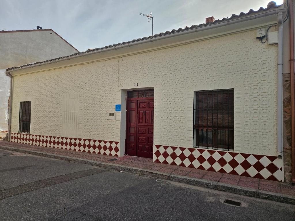 un edificio blanco con una puerta roja en una calle en La Nava, casa de pueblo con patio y calefacción con chimenea, en Nava de la Asunción