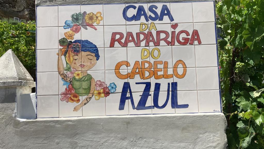 a sign for a restaurant with a woman on a tile wall at A Casa da Rapariga de Cabelo Azul in Manteigas