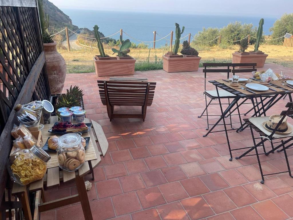 a patio with tables and chairs and a view of the ocean at B&B La Torre in Realmonte