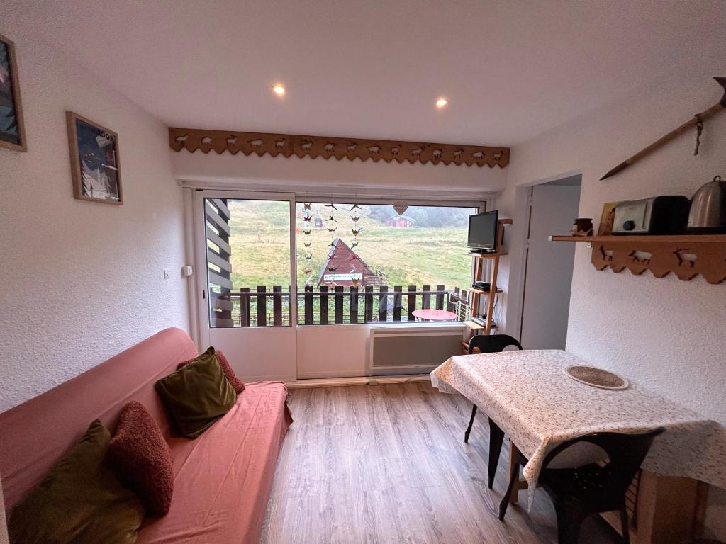 - un salon avec un canapé rose et une grande fenêtre dans l'établissement Appartement cosy avec balcon, à Puyvalador