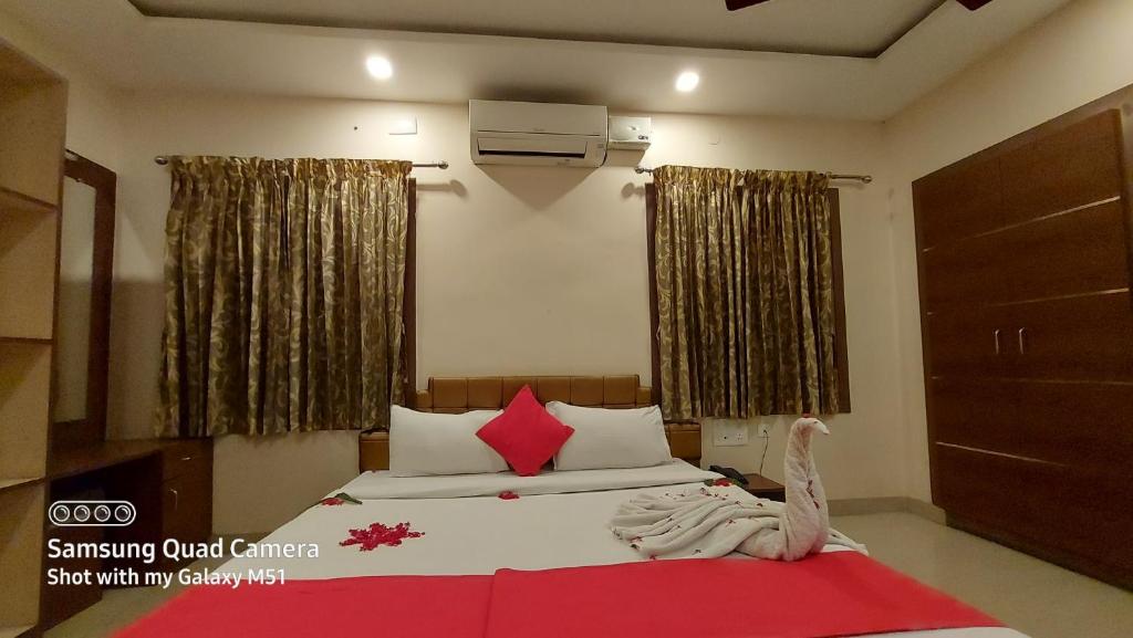 a bedroom with a bed with red and white pillows at Sri Kamadhenu Residency in Coimbatore