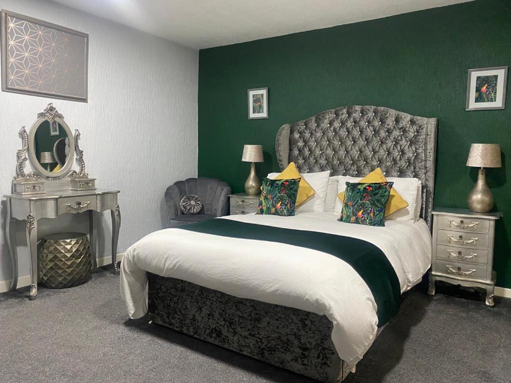 um quarto com uma cama grande e uma parede verde em Saphire Glasgow Apartments em Giffnock