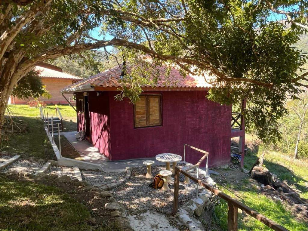 een rood huis met een veranda en een boom bij Solar dos Canários in São Bento do Sapucaí