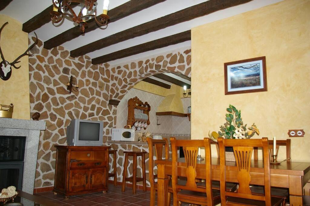 cocina y comedor con mesa y TV en Casa Rural Cristina I en San Pablo de los Montes