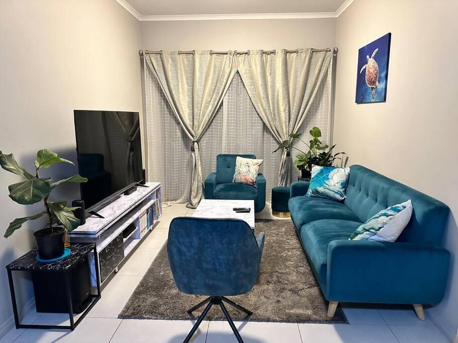 een woonkamer met een blauwe bank en een televisie bij Maria’s Place in Midrand