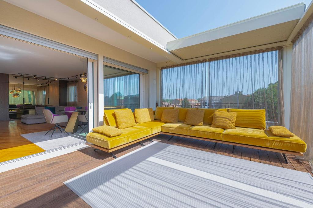un sofá amarillo en la sala de estar con una ventana grande en Venice New Luxury Penthouse - free parking and roof terrace, en Mestre
