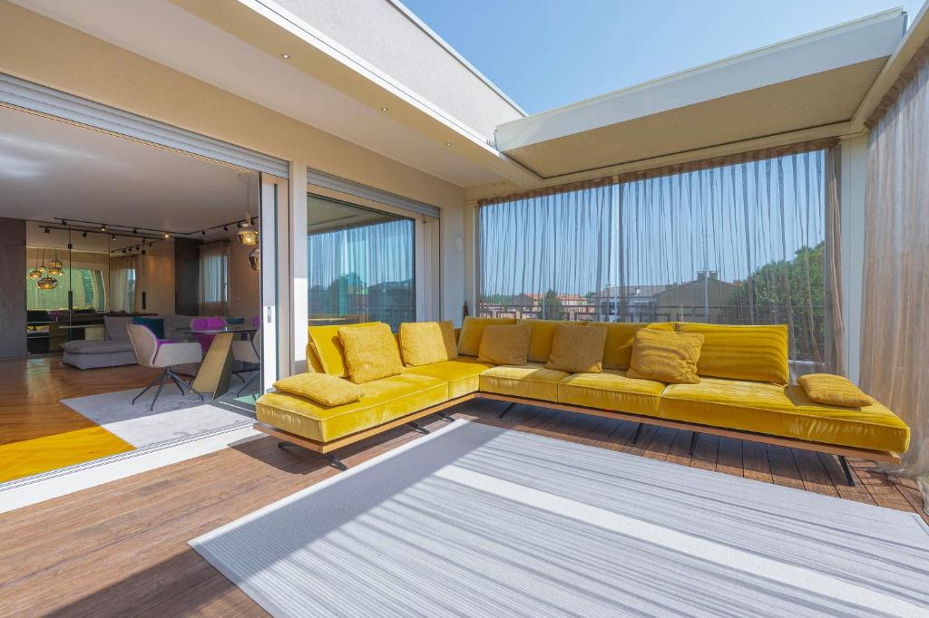 a yellow couch in a living room with a large window at Venice New Luxury Penthouse - free parking and roof terrace in Mestre