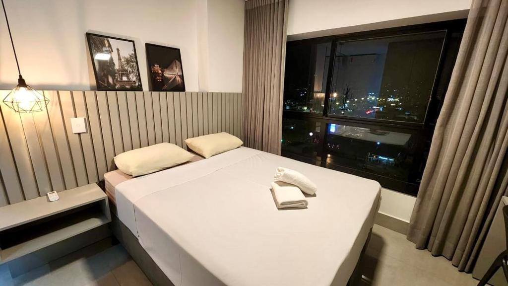 a bedroom with a white bed and a window at Uma Linda Vista com Quarto Privativo no Ed. Vertigo in Campo Grande