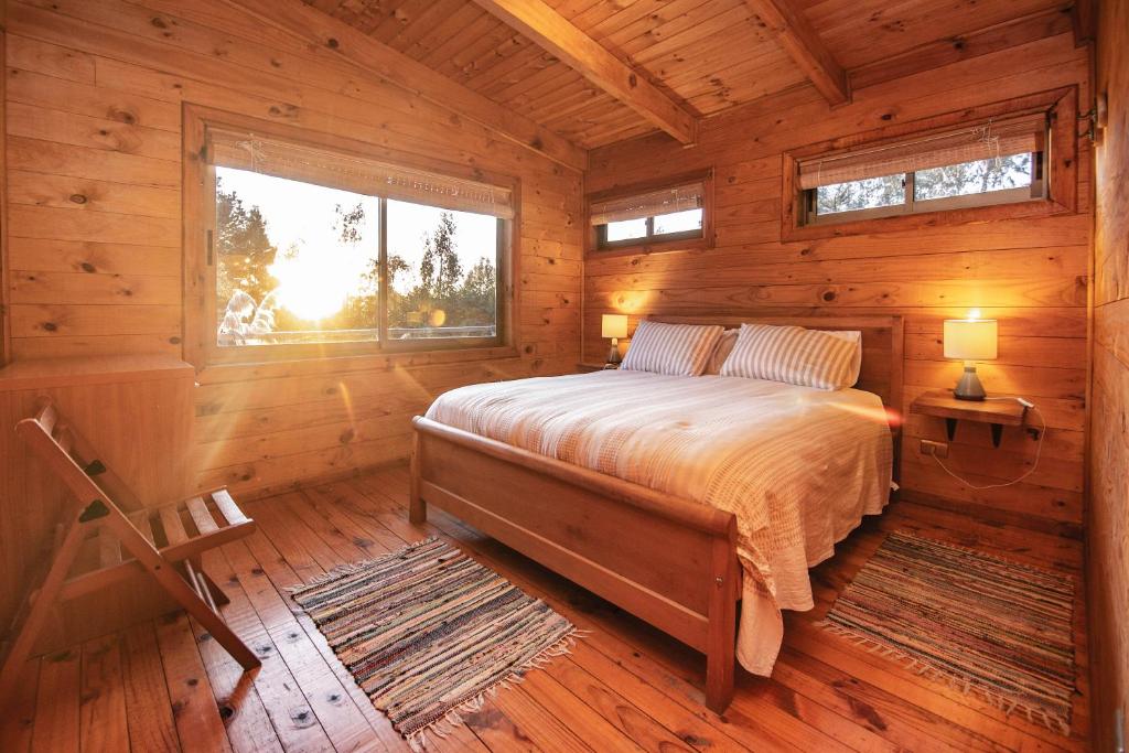 a bedroom with a bed in a log cabin at Cabañas Bosques de Puertecillo in Puertecillo