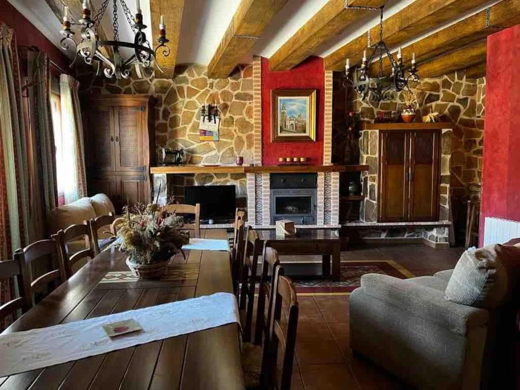 a living room with a table and a stone fireplace at Casa Rural Cristina III in San Pablo de los Montes