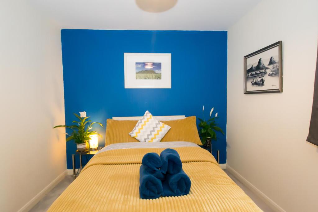 een slaapkamer met blauwe muren en een bed met blauwe schoenen erop bij Spacious 2 Beds & 2 Baths Flat at City Center in Birmingham