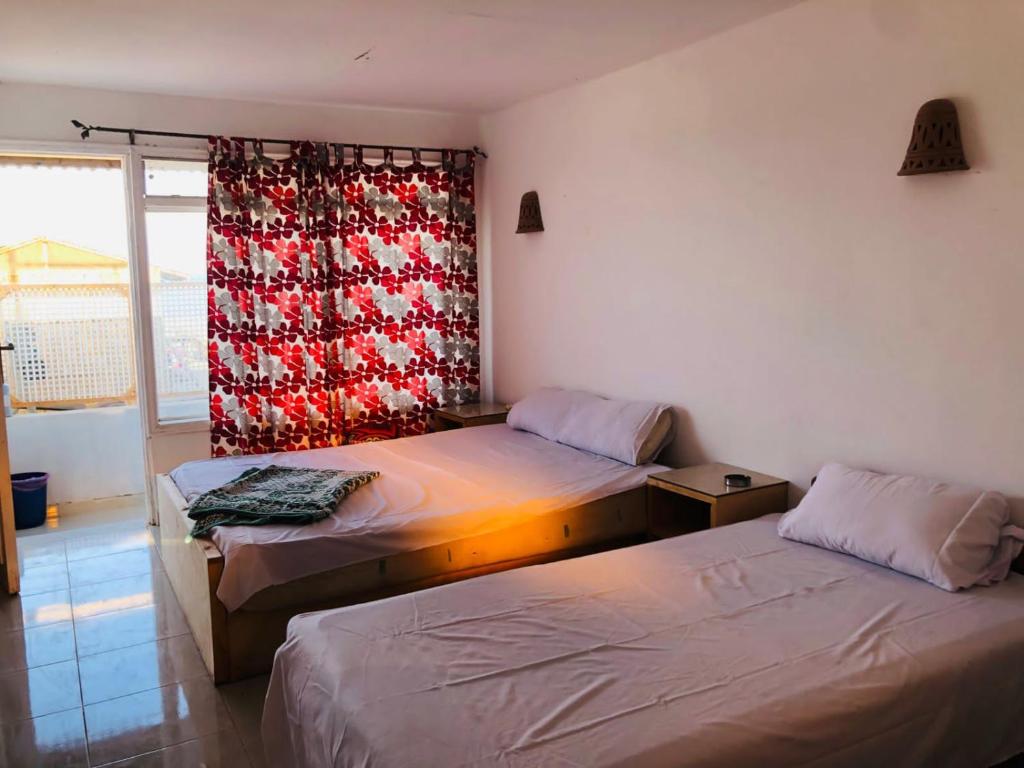 a room with two beds and a window with a curtain at فللبررر in Nuweiba