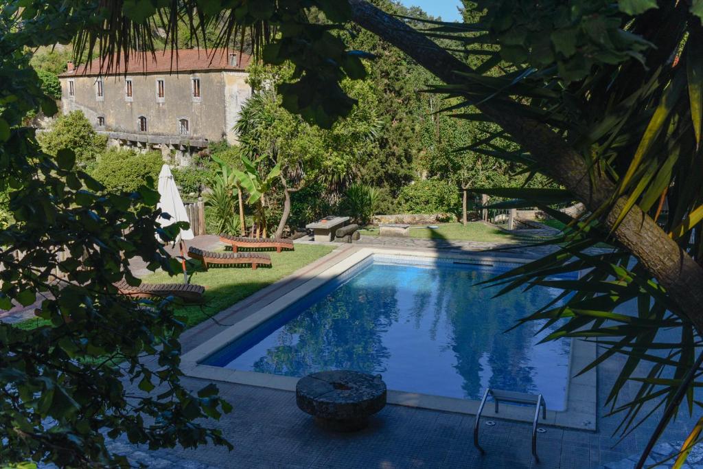 a swimming pool in a yard with a building in the background at Quinta de Rio Alcaide in Porto de Mós