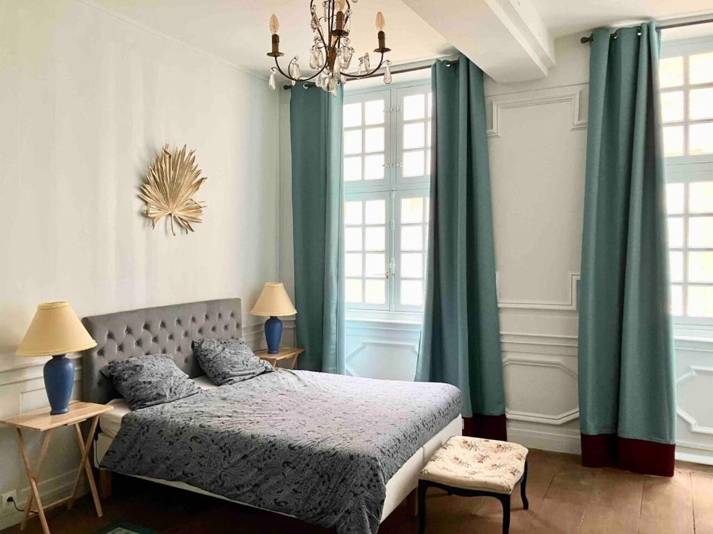 1 dormitorio con 1 cama con cortinas verdes y lámpara de araña en Appartement Intra-Muros - 2 chambres en Saint-Malo