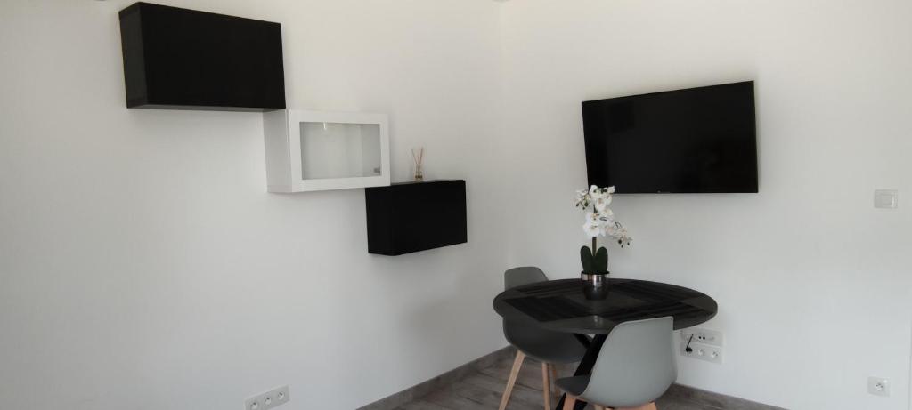 a room with a table and a tv on a wall at Le Pavillon Les BUISSONNETS in Salon-de-Provence