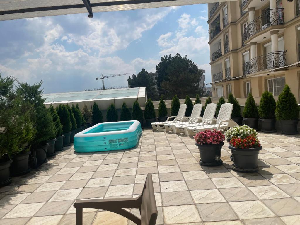 a patio with a pool and chairs and a building at Sonny’s Penthouse in Gnjilane