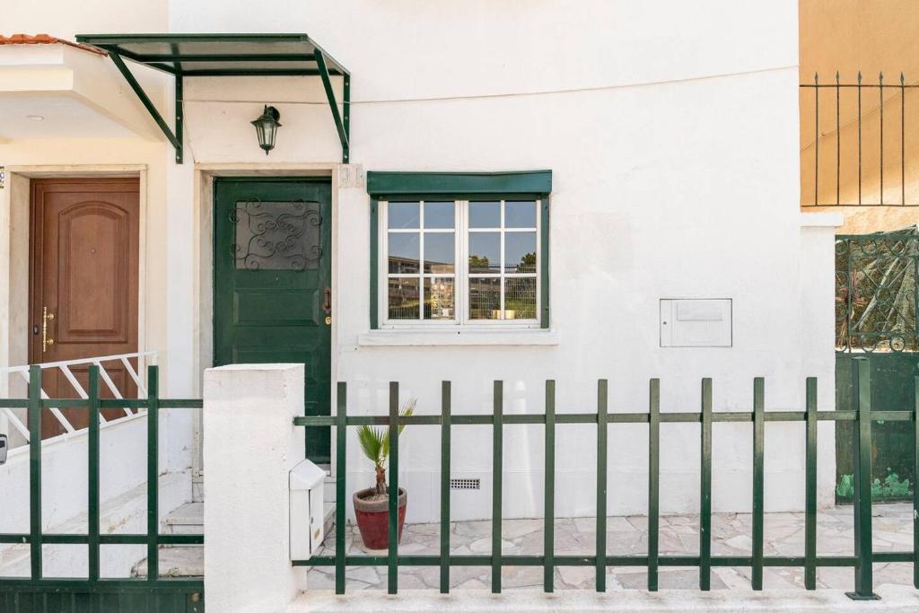 a white house with a green door and a fence at Cozy Haven Retreat in Lisbon