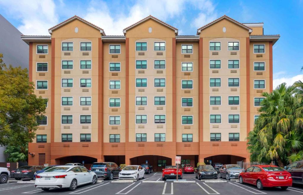 un grand bâtiment avec des voitures garées devant lui dans l'établissement Extended Stay America Premier Suites - Miami - Coral Gables, à Miami