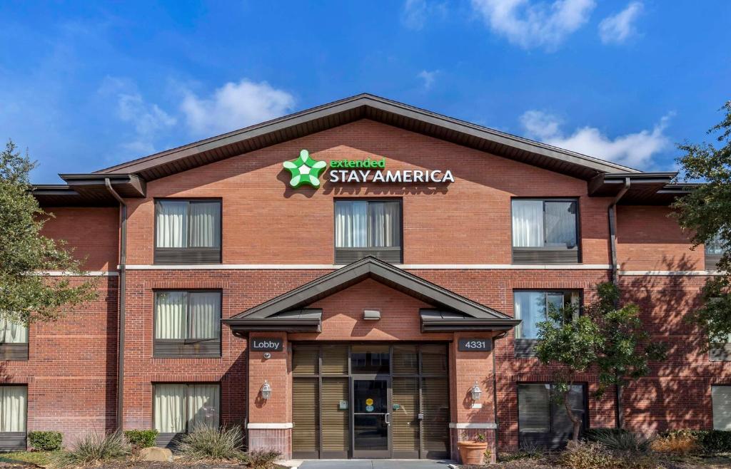 un bâtiment en brique rouge avec un panneau. dans l'établissement Extended Stay America Suites - San Antonio - Colonnade - Medical, à San Antonio