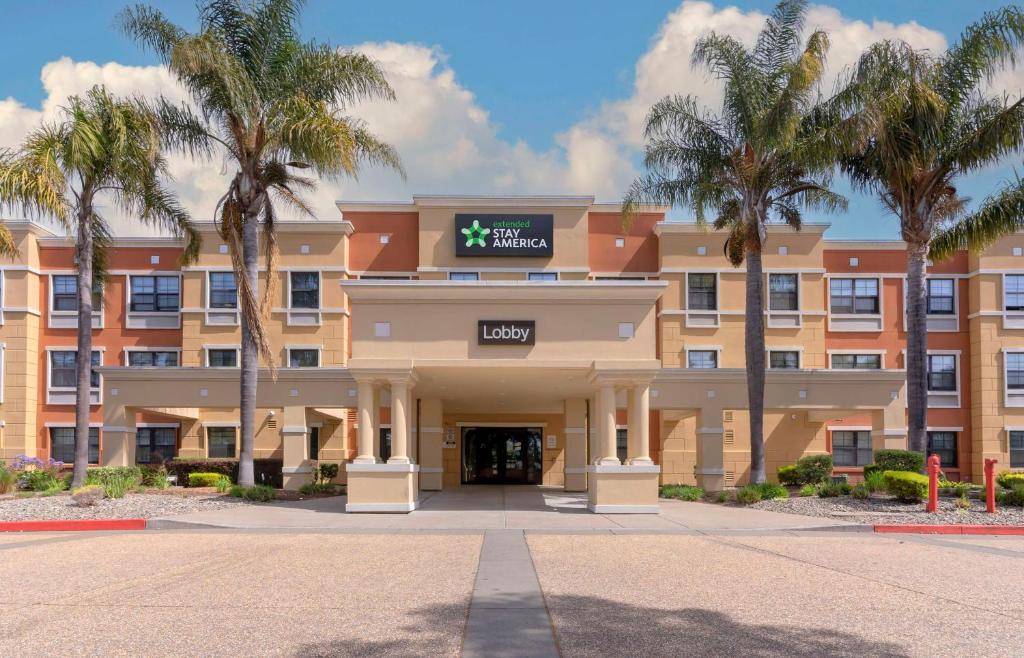 a hotel with palm trees in front of a building at Extended Stay America Suites - Oakland - Alameda Airport in Alameda