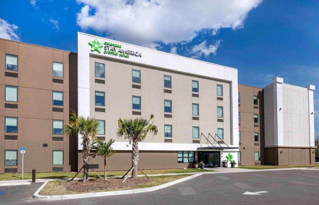 タンパにあるExtended Stay America Premier Suites - Tampa - Fairgrounds - Casinoのヤシの木が目の前に広がるホテルの建物