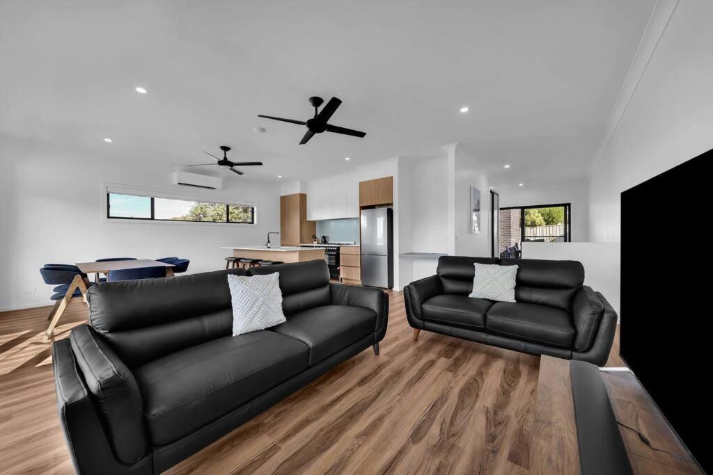 a living room with two black leather couches at Kira Lani - Pet friendly Tura in Tura Beach